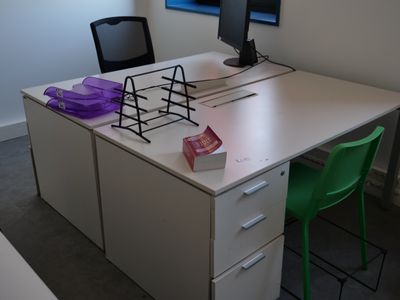 a white desk with a computer monitor and a green chair