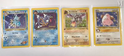 four pokemon cards are lined up on a white surface