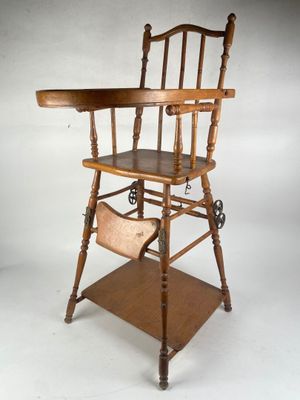 an old wooden high chair sitting on top of a wooden shelf