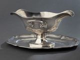 une saucière en argent posée sur un plateau en argent, sur une table