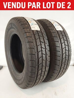 une paire de pneus posés sur une surface blanche, sur fond rouge