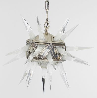 une lampe en cristal suspendue à une chaîne sur un mur blanc
