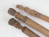three wooden sticks with carvings on them on a white surface