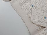 a white sweater with blue buttons on it sitting on a table