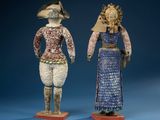 two figurines of a woman and a man standing next to each other on a blue surface