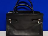 un sac à main en cuir noir posé sur une table blanche