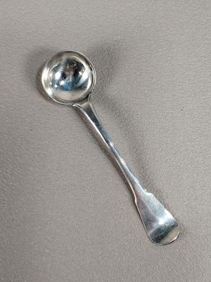 une cuillère en argent avec un manche de cuillère sur une table