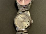a silver watch with a pink face on a table