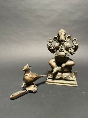 brass statue of ganji with a bird on a stand