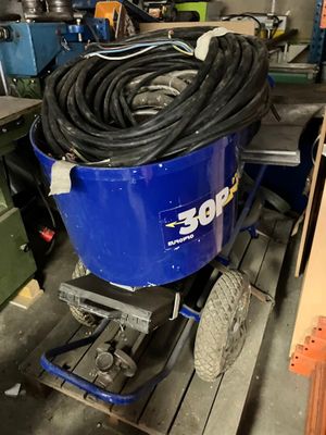 un seau bleu avec un tuyau posé sur un chariot dans un garage