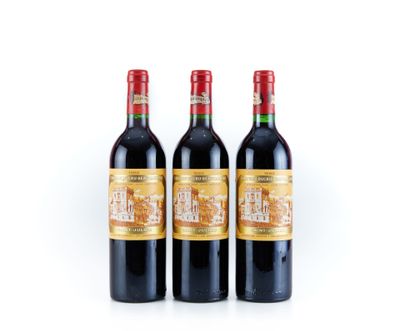 trois bouteilles de vin rouge posées l'une à côté de l'autre sur une surface blanche