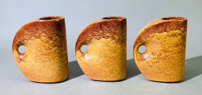 trois vases bruns percés de trous, posés sur une table