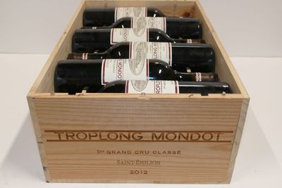 des bouteilles de vin rouge dans un coffret en bois posé sur une surface blanche