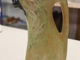 a green vase with a dog head on it on a table