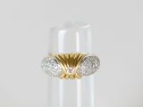 un gros plan d'une bague en or et diamants posée sur un verre