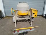 concrete mixer sitting in front of a garage next to a tool box