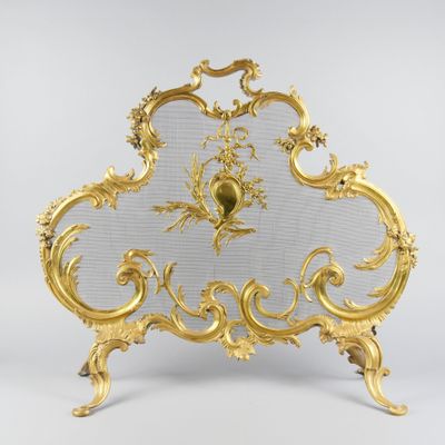 un pare-feu en or richement décoré, surmonté d'une horloge