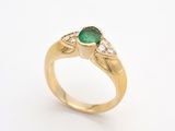 gros plan d'une bague en or avec une pierre verte et des diamants