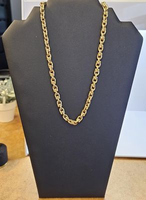 un collier à chaîne en or posé sur un présentoir noir pour mannequin