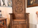 une chaise en bois dans une pièce où est accroché un tableau au mur