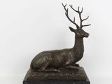 sculpture représentant un cerf assis sur un socle en marbre, sur fond blanc