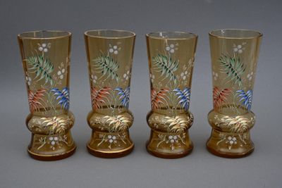 trois vases dorés ornés de motifs floraux sont alignés sur une surface grise