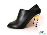 black leather high heeled shoe with gold heeling on a white surface
