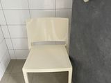 a white chair sitting in the corner of a bathroom