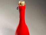 a red glass bottle with a gold cap on it