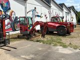 trois chariots élévateurs garés devant un bâtiment orné d'une fresque murale sur l'un de ses côtés