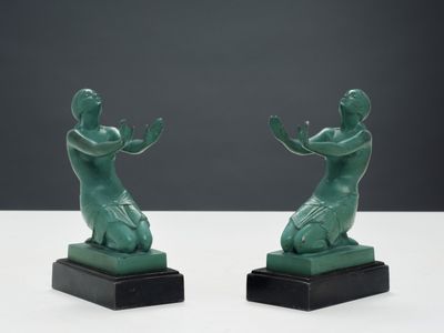 deux statues vertes représentant une femme et un homme, posées sur une surface blanche