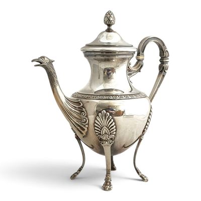 une théière ancienne en argent, ornée d'une poignée en forme de paon, posée sur un socle
