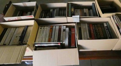 de nombreux livres rangés dans des cartons posés par terre