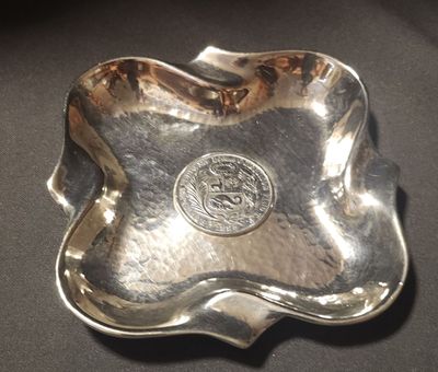 an image of a silver plate with a silver seal on it