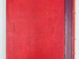 an old red book sitting on top of a white table