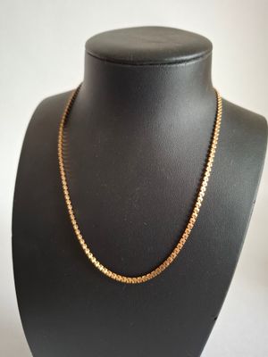 a gold chain necklace on a mannequin neck