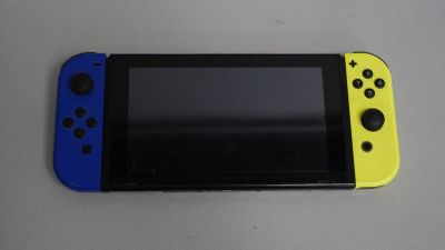 La Nintendo Switch Lite est posée sur une table, accompagnée d'une manette bleue et jaune.