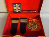 une boîte rouge contenant une médaille, une médaille et une paire de chaussures