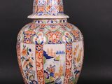 an orange and blue vase with a bird sitting on top of it