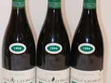 trois bouteilles de vin sont alignées sur une surface blanche