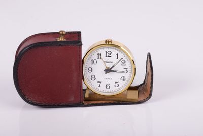 a small clock sitting on top of a leather case