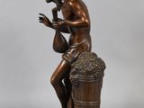 a bronze statue of a man sitting on top of a barrel