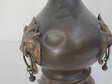 a bronze vase with a lion head decoration on it