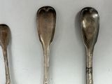three silver spoons are lined up on a white surface
