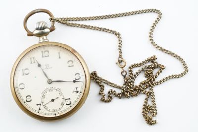 une montre de poche en or avec une chaîne sur fond blanc