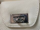 a close up of a white purse with a metal buckle