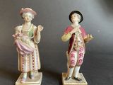 pair of figurines of a man and a woman holding a baby
