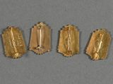 four pieces of gold foil on a gray surface
