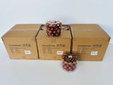 Trois boîtes de cerises enrobées de chocolat sont posées sur une table, à côté d'un bocal de cerises.