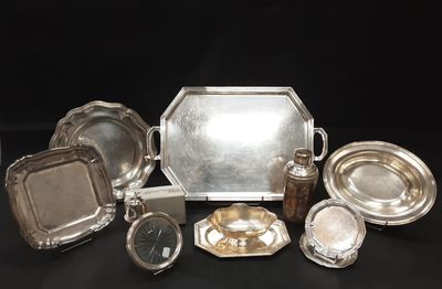 many silver plates and trays sitting on a table